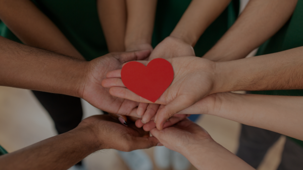 background of people's hands meeting in the center holding a heart